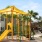 a yellow playground with trees and buildings